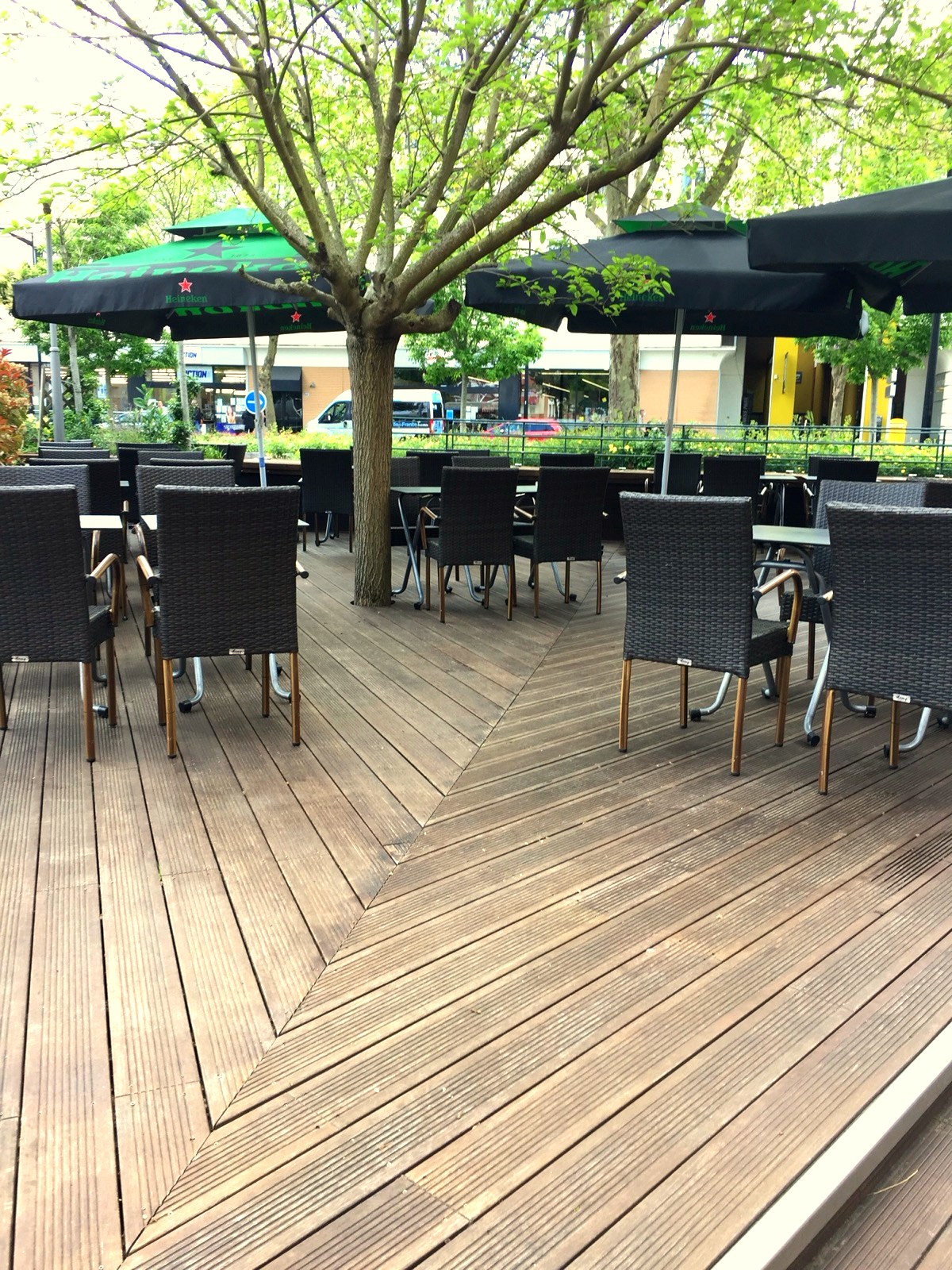 Tables alignées sur la terrasse en lames de bois du Café du Marché
